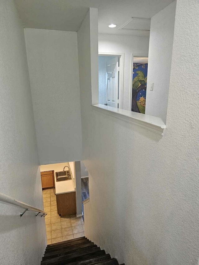 staircase featuring tile patterned floors and sink