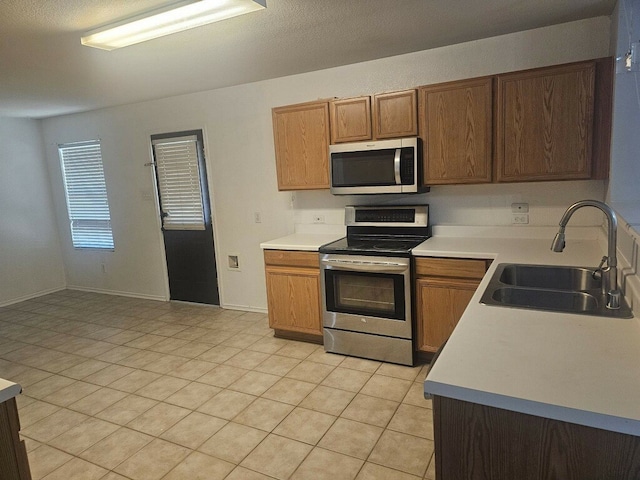 kitchen with sink, light tile patterned floors, and stainless steel appliances