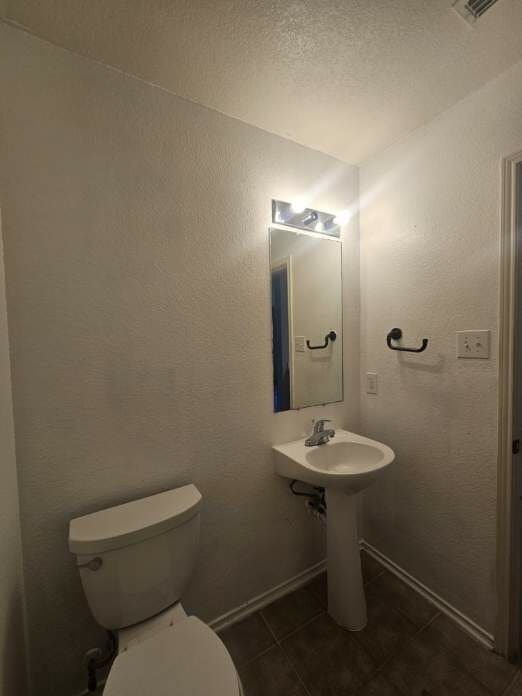 bathroom with tile patterned floors, toilet, and a textured ceiling