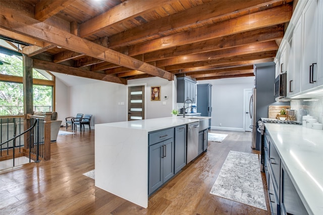 kitchen with white cabinetry, a kitchen island with sink, wooden ceiling, beamed ceiling, and stainless steel appliances