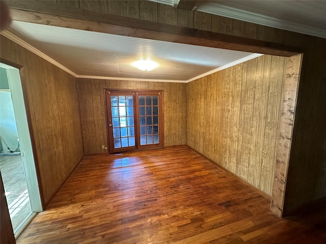 unfurnished room featuring wooden walls, dark hardwood / wood-style floors, beam ceiling, and crown molding