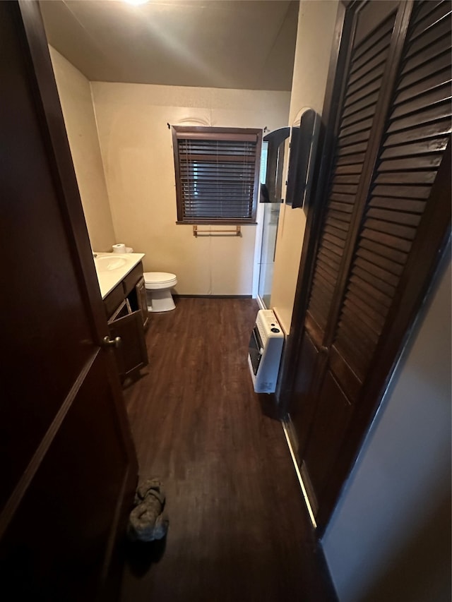 bathroom with vanity, toilet, heating unit, and hardwood / wood-style flooring