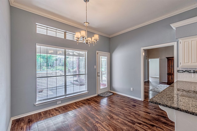 unfurnished dining area featuring crown molding, dark wood-type flooring, and a notable chandelier