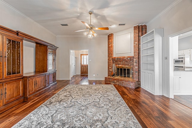 living room featuring ceiling fan, ornamental molding, dark hardwood / wood-style floors, and a brick fireplace