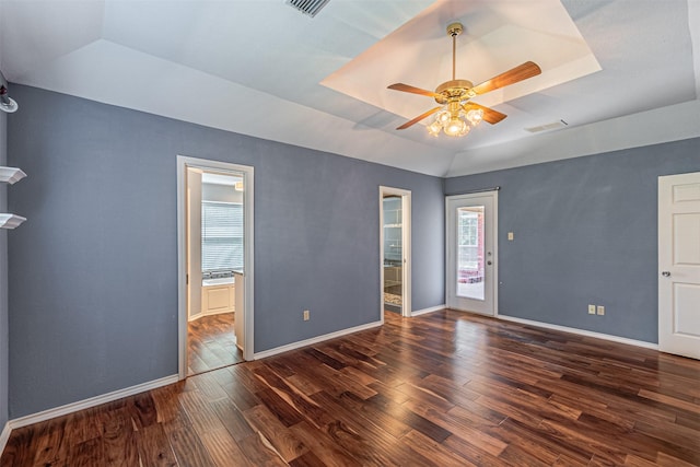 unfurnished room with dark hardwood / wood-style flooring, ceiling fan, and a tray ceiling