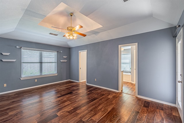 empty room with dark hardwood / wood-style floors, ceiling fan, and a tray ceiling