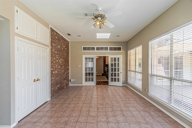 interior space with a skylight, brick wall, ceiling fan, and french doors