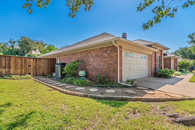 view of side of home with a garage, a yard, and central air condition unit