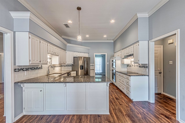 kitchen with sink, dark stone counters, kitchen peninsula, stainless steel appliances, and white cabinets