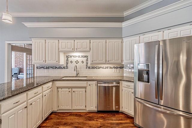 kitchen with sink, decorative backsplash, stainless steel appliances, and dark stone counters