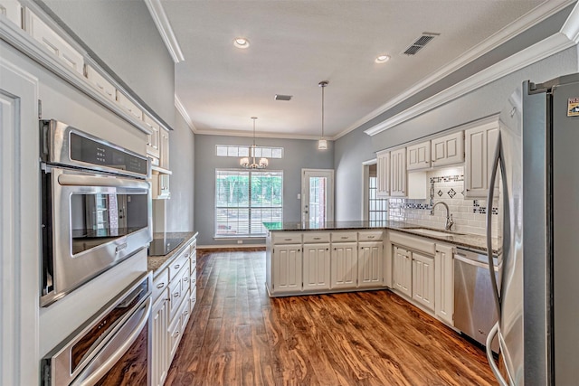 kitchen with sink, a chandelier, kitchen peninsula, stainless steel appliances, and decorative backsplash