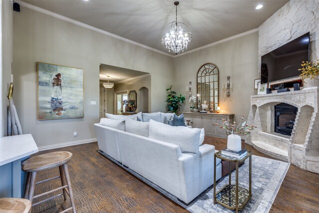 living room with a notable chandelier, dark hardwood / wood-style floors, a fireplace, and crown molding