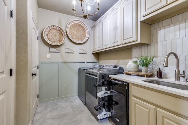 clothes washing area with cabinets, sink, an inviting chandelier, light tile patterned floors, and separate washer and dryer