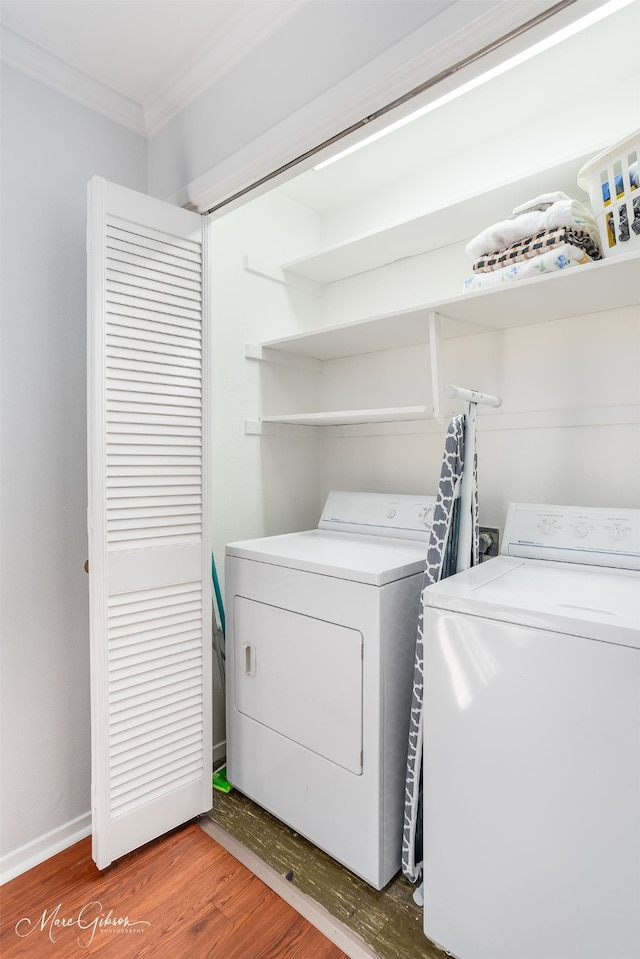 laundry area with crown molding, washing machine and clothes dryer, and hardwood / wood-style flooring