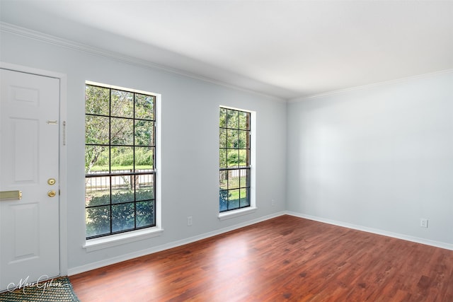 empty room with hardwood / wood-style flooring, crown molding, and plenty of natural light