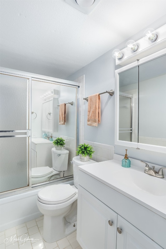 full bathroom featuring tile patterned flooring, a textured ceiling, bath / shower combo with glass door, vanity, and toilet