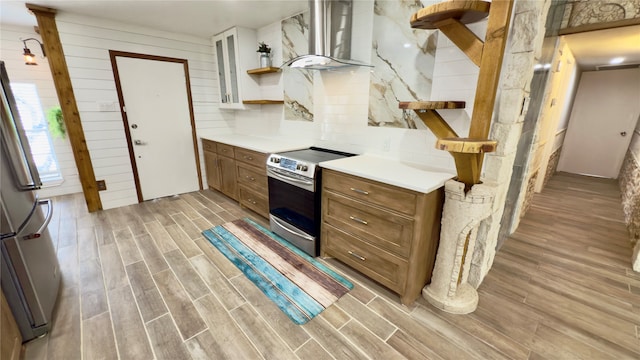 kitchen with tasteful backsplash, range hood, wood walls, light hardwood / wood-style flooring, and stainless steel appliances