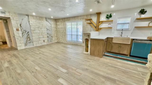 kitchen featuring dishwasher, light wood-type flooring, sink, and a textured ceiling