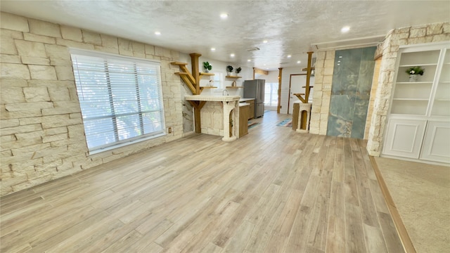 unfurnished living room featuring light hardwood / wood-style floors and a textured ceiling