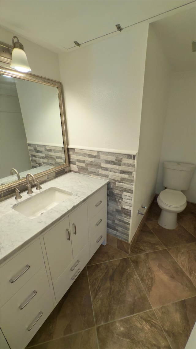 bathroom featuring vanity, toilet, and tasteful backsplash