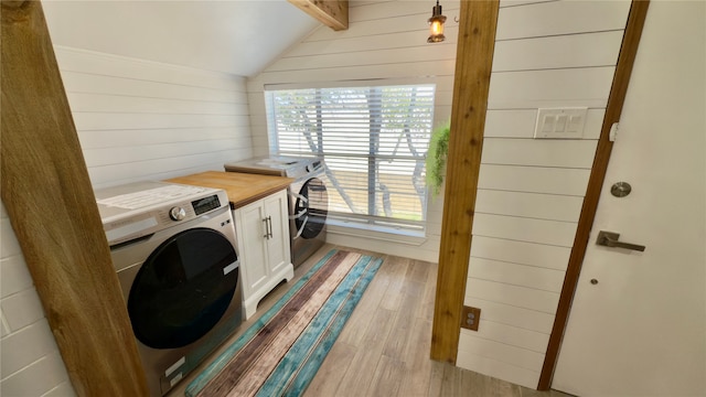 laundry room with cabinets, light hardwood / wood-style flooring, and wood walls