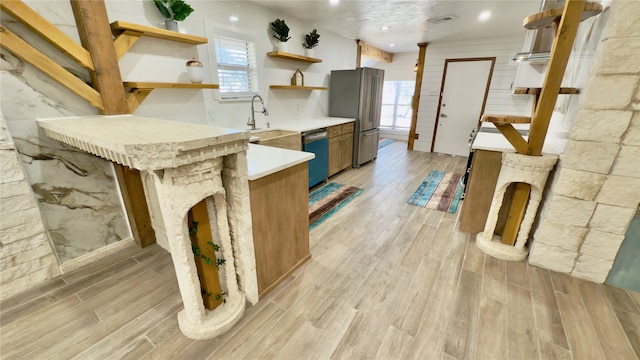 kitchen featuring sink, kitchen peninsula, a kitchen breakfast bar, appliances with stainless steel finishes, and light hardwood / wood-style floors