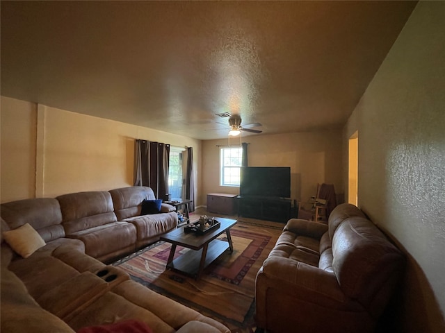 living room with a textured ceiling, wood-type flooring, and ceiling fan