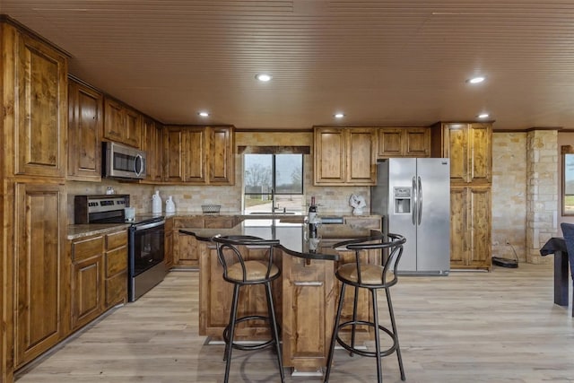 kitchen with a kitchen breakfast bar, stainless steel appliances, a center island, light hardwood / wood-style flooring, and sink