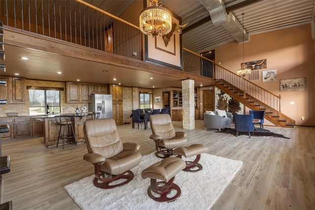 living room featuring a high ceiling, beam ceiling, light hardwood / wood-style floors, and ornate columns