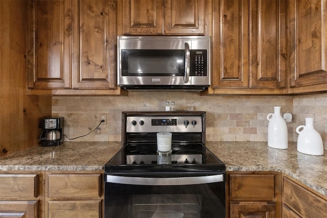 kitchen with light stone countertops, stainless steel appliances, and tasteful backsplash