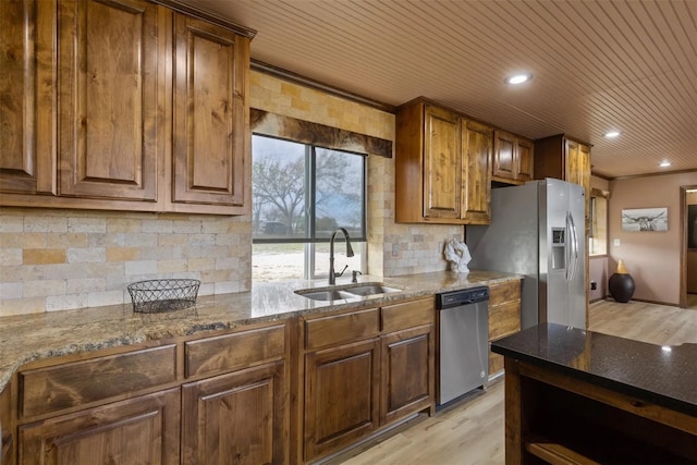 kitchen featuring dark stone counters, stainless steel appliances, light wood-type flooring, and sink