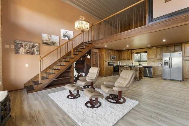 living room featuring an inviting chandelier, a towering ceiling, and light hardwood / wood-style floors