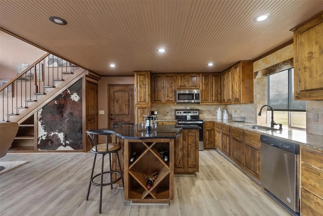 kitchen with sink, a kitchen island, stainless steel appliances, wooden ceiling, and light wood-type flooring