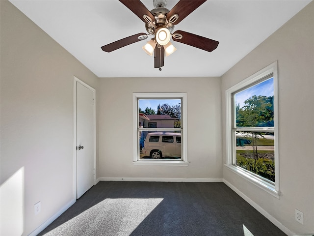 empty room featuring dark carpet and ceiling fan