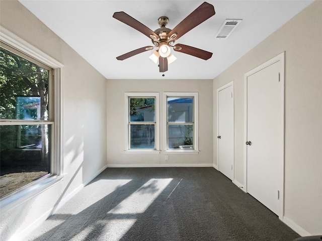 spare room with dark colored carpet and ceiling fan