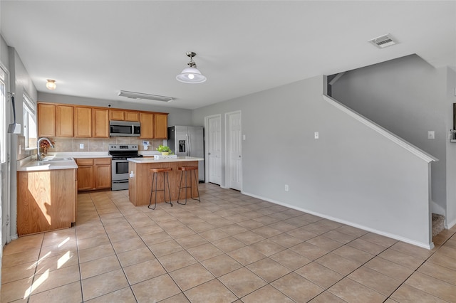6001 Red Drum Dr, Fort Worth, TX 76179 - kitchen with stainless steel appliances, a sink, light countertops, a center island, and light tile patterned flooring