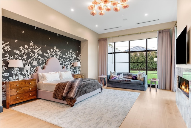 bedroom featuring a notable chandelier, wood-type flooring, and a fireplace