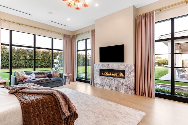 bedroom with a high end fireplace and light hardwood / wood-style floors