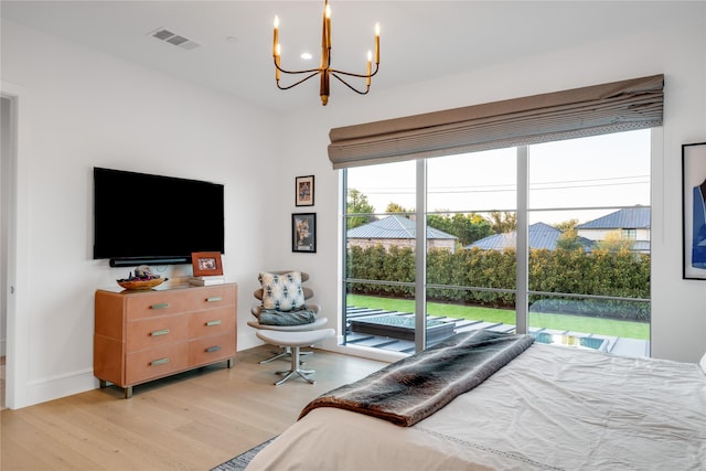 bedroom featuring an inviting chandelier, access to outside, and light hardwood / wood-style flooring