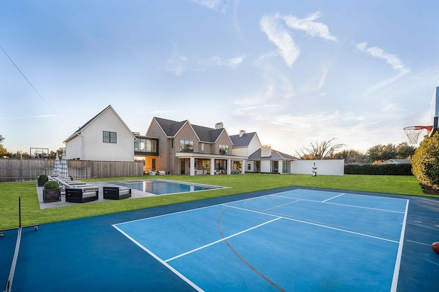 view of tennis court with a yard and basketball hoop