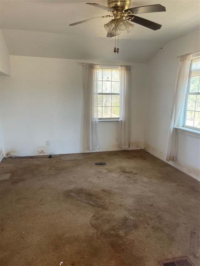 spare room featuring a wealth of natural light, vaulted ceiling, carpet floors, and ceiling fan