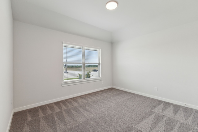 empty room with vaulted ceiling, carpet floors, and baseboards