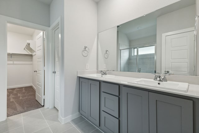 bathroom featuring tile patterned flooring, a sink, a shower stall, and a spacious closet
