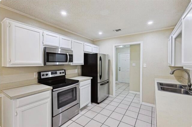 kitchen featuring stainless steel appliances, white cabinets, a textured ceiling, and sink