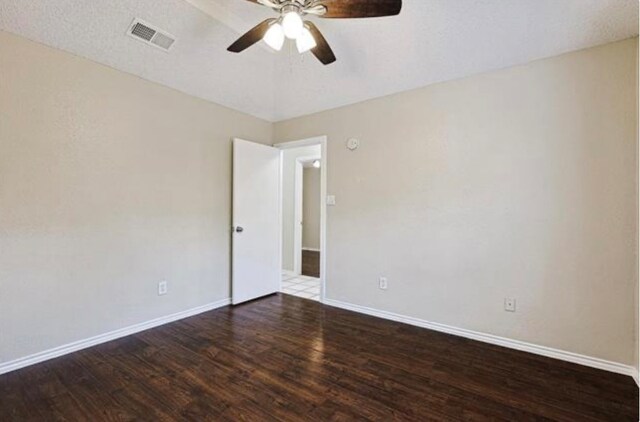 spare room featuring a textured ceiling, ceiling fan, and dark wood-type flooring