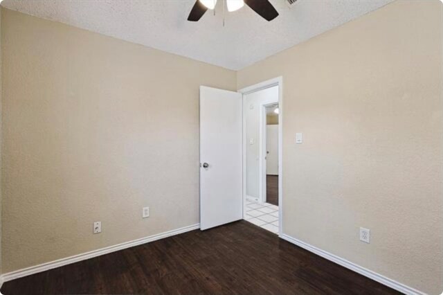 unfurnished room with ceiling fan, a textured ceiling, and dark hardwood / wood-style floors