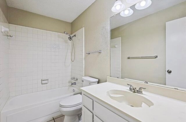 full bathroom with vanity, a textured ceiling, tiled shower / bath, and toilet