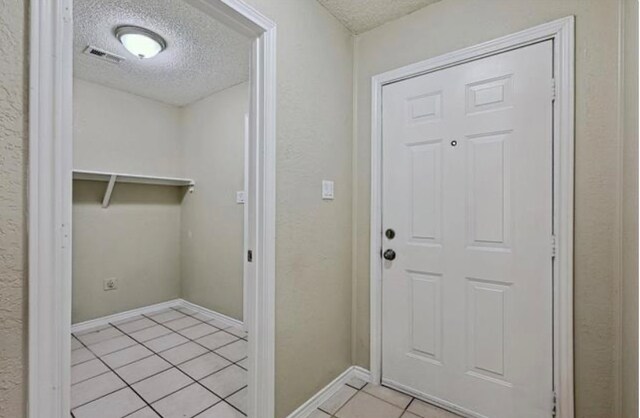 entryway with a textured ceiling and light tile patterned floors