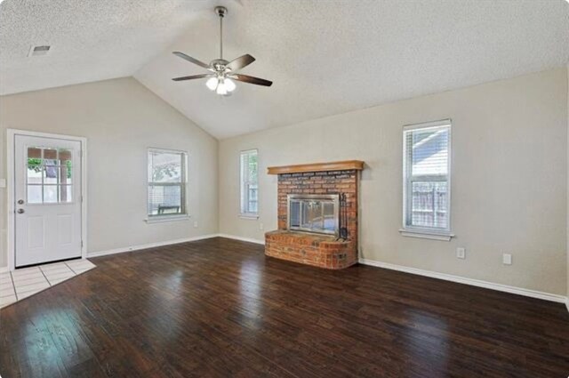 unfurnished living room featuring hardwood / wood-style flooring, a fireplace, vaulted ceiling, and a wealth of natural light