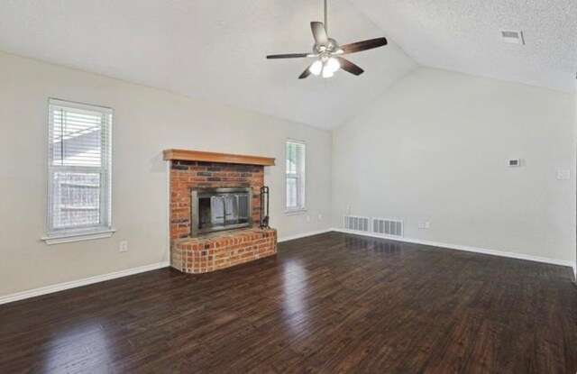 unfurnished living room featuring ceiling fan, a textured ceiling, dark wood-type flooring, high vaulted ceiling, and a fireplace